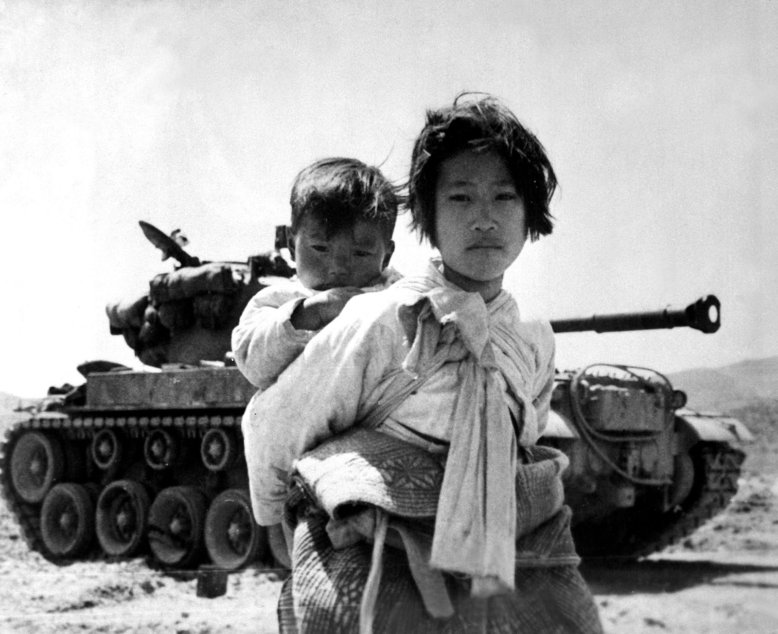 Koreansk jente bærer et lite barn under Koreakrigen i 1951