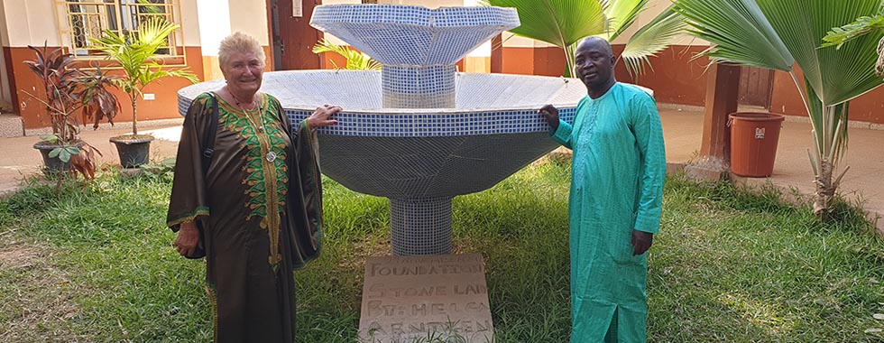 Helga Arntzen og Momodou Jain foran monumentet på skolen ble bygget